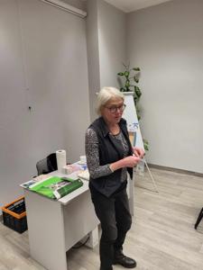 Na zdjęciu znajduje się Pani prowadząca warsztaty. Zdjęcie wykonano w bibliotece.