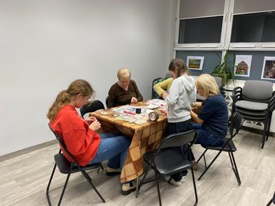Na zdjęciach znajdują się uczestnicy warsztatów. Uczestnicy siedzą i wykonują rękodzieło.