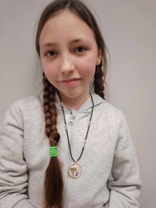 Na zdjęciu znajduje się uczestniczka warsztatów. Uczestniczka trzyma w rękach biżuterię.