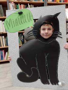 Na zdjęciu znajduje się chłopiec trzymający głowę w ramce kota.