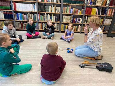 Na zdjęciu znajdują się uczestnicy zajęć. Dzieci siedzą w kręgu na podłodze.