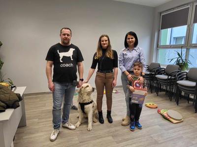 Na zdjęciu zgadują się uczestnicy zajęć. Na zdjęciu znajduje się pies.