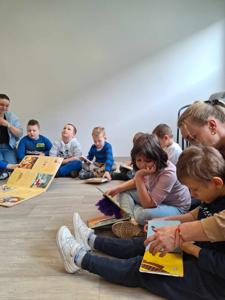 Zdjęcie przedstawia uczestników lekcji bibliotecznej. Zdjęcie wykonano w bibliotece.
