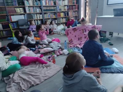 Zdjęcie przedstawia uczestników kina w bibliotece. Dzieci oglądają bajkę. Zdjęcie wykonano w bibliotece.