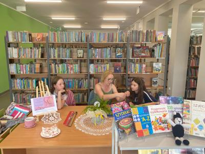 Zdjęcie przedstawia uczestników akcji Dzień Dziergania w Miejscach Publicznych. Zdjęcie wykonano w bibliotece.