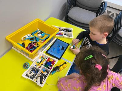 Zdjęcie przestawia uczestników zajęć Zabawa i Programowanie. Zdjęcie wykonano w Bibliotece.