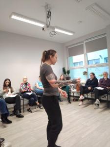 Zdjęcie przedstawia uczestniczki warsztatów  samoobrony. Zdjęcie wykonano w Bibliotece.