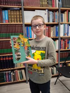 Na zdjęciu znajduje się uczestnik zajęć o tematyce jesiennej. Zdjęcie wykonano w bibliotece.