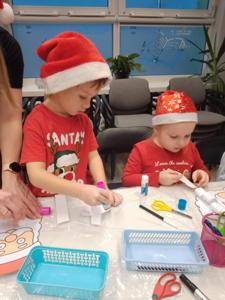 Na zdjęciu znajdują się dzieci siedzące przy stołach. Zdjęcie wykonano w bibliotece.