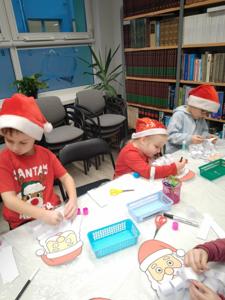 Na zdjęciu znajdują się dzieci siedzące przy stołach. Zdjęcie wykonano w bibliotece.