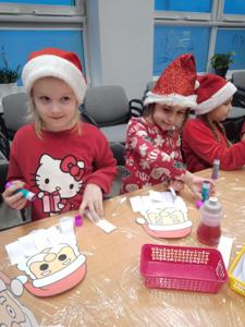 Na zdjęciu znajdują się dzieci siedzące przy stołach. Zdjęcie wykonano w bibliotece.