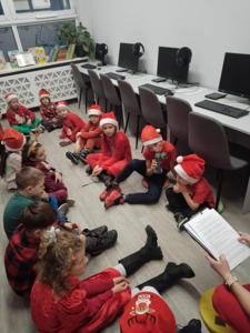 Na zdjęciu znajdują się dzieci siedzące na podłodze. Zdjęcie wykonano w bibliotece.