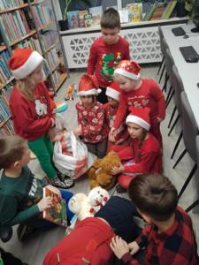 Na zdjęciu znajdują się dzieci siedzące na podłodze. Zdjęcie wykonano w bibliotece.