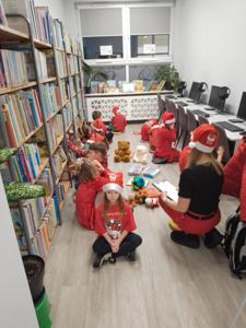 Na zdjęciu znajdują się dzieci siedzące na podłodze. Zdjęcie wykonano w bibliotece.