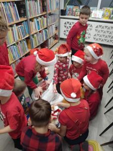 Na zdjęciu znajdują się dzieci, które wyciągają przedmioty z worka. Zdjęcie wykonano w bibliotece.