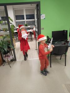 Na zdjęciu znajdują się dzieci trzymające w ręce Mikołaje. Zdjęcie wykonano w bibliotece.