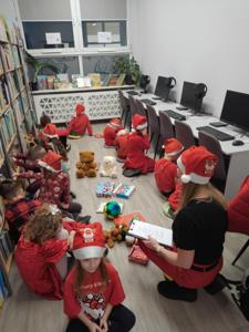 Na zdjęciu znajdują się dzieci siedzące na podłodze. Zdjęcie wykonano w bibliotece.