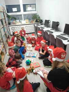 Na zdjęciu znajdują się dzieci siedzące na podłodze. Zdjęcie wykonano w bibliotece.