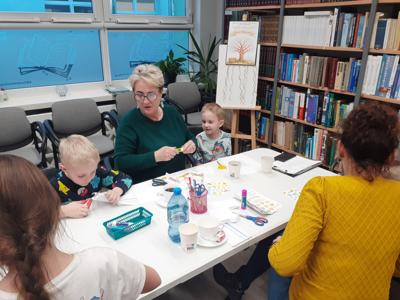Na zdjęciu znajdują się uczestnicy zajęć. Uczestnicy siedzą. W tle książki.