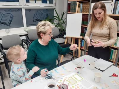 Na zdjęciu znajdują się uczestnicy zajęć. Uczestnicy siedzą. W tle książki.