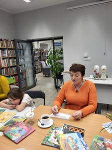 Na zdjęciu znajdują się uczestnicy zajęć. Uczestnicy siedzą. W tle książki.