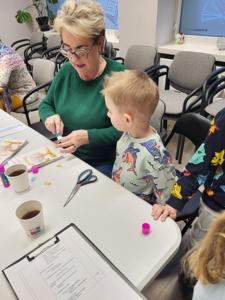 Na zdjęciu znajdują się uczestnicy zajęć. Uczestnicy siedzą. W tle książki.