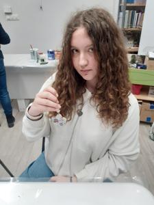 Na zdjęciu znajdują się Panie trzymające drewniane przedmioty. Zdjęcie wykonano w bibliotece.