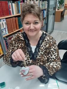 Na zdjęciu znajdują się Panie trzymające drewniane przedmioty. Zdjęcie wykonano w bibliotece.