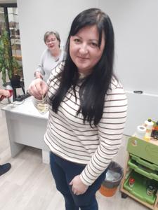 Na zdjęciu znajdują się Panie trzymające drewniane przedmioty. Zdjęcie wykonano w bibliotece.