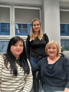 Na zdjęciu znajdują się Panie trzymające drewniane przedmioty. Zdjęcie wykonano w bibliotece.