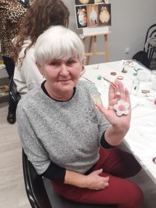 Na zdjęciu znajdują się Panie trzymające drewniane przedmioty. Zdjęcie wykonano w bibliotece.