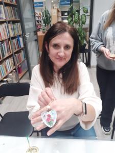 Na zdjęciu znajdują się Panie trzymające drewniane przedmioty. Zdjęcie wykonano w bibliotece.