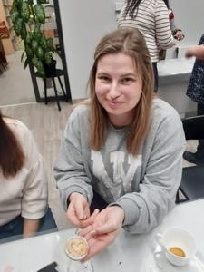 Na zdjęciu znajdują się Panie trzymające drewniane przedmioty. Zdjęcie wykonano w bibliotece.