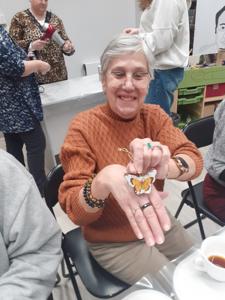 Na zdjęciu znajdują się Panie trzymające drewniane przedmioty. Zdjęcie wykonano w bibliotece.