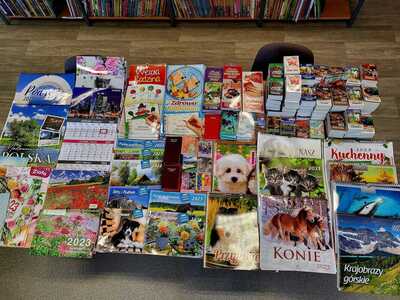 Na zdjęciu znajdują się kalendarze poukładane na stole. Zdjęcie wykonano w bibliotece.