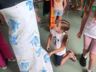Dziewczynki przycinają biały materiał w niebieskie kwiatki