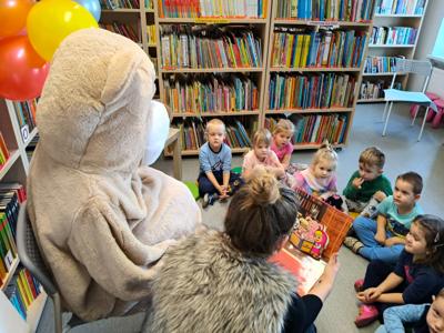 Pani bibliotekarka czyta książkę dzieciom przy misiu.