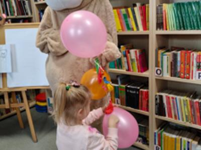 Miś trzyma balony, gdy dzieci rozbijają je wykałaczką
