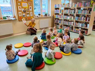 Pani bibliotekarka czyta książkę grupie dzieci.