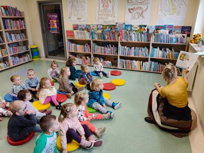  Pani bibliotekarka czyta książkę grupie dzieci.