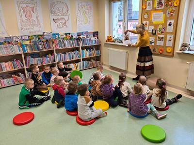 Pani bibliotekarka czyta książkę grupie dzieci.
