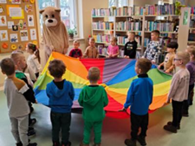 Miś i dzieci trzymają chustę.