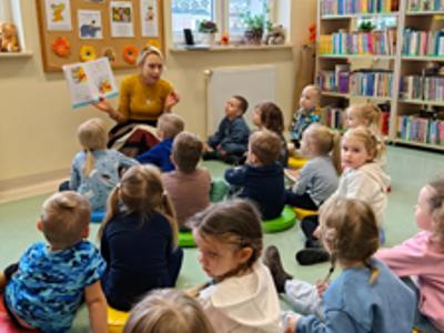 Pani bibliotekarka czyta książkę grupie dzieci.