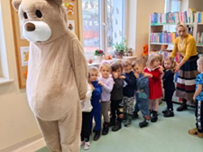 Miś stoi na początku ludzkiego pociągu.