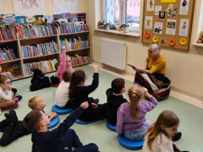  Pani bibliotekarka czyta książkę grupie dzieci.