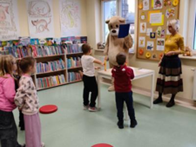 Miś czyta pytania do quizu, a dzieci próbują odpowiedzieć.