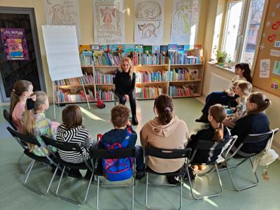 Grupa dzieci siedzących przed aktorką Anną Kamińską