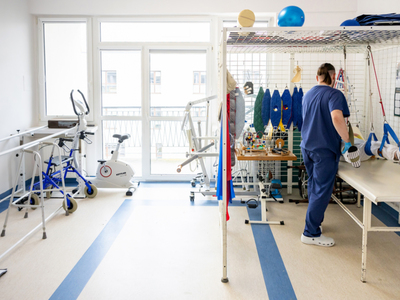 Sala rehabilitacyjna. Rehabilitant ćwiczy z pacjentem 