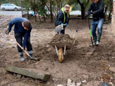 Pracownicy szpitala pomagają w sprzątaniu terenu gospodarstwa po powodzi 