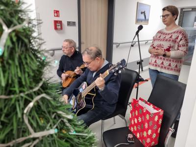 Dwóch muzyków grających na gitarze i mandolinie i śpiewająca kobieta